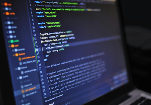 Programmers collaborating and writing code on multiple screens